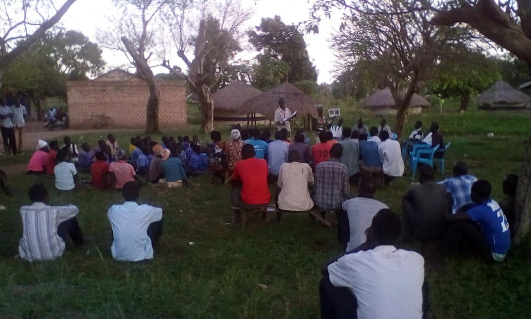Community members discussing challenges during an outdoor health session